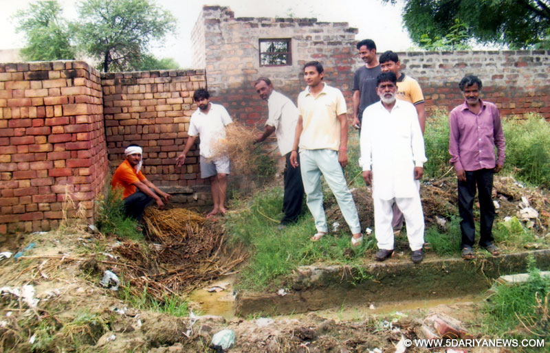विजय सिंह द्वारा पंचायती बरसाती नाले पर किए गए अवैध निर्माण को दिखाते ग्रामीण व घरों के पास इकट्ठा हुआ पानी।