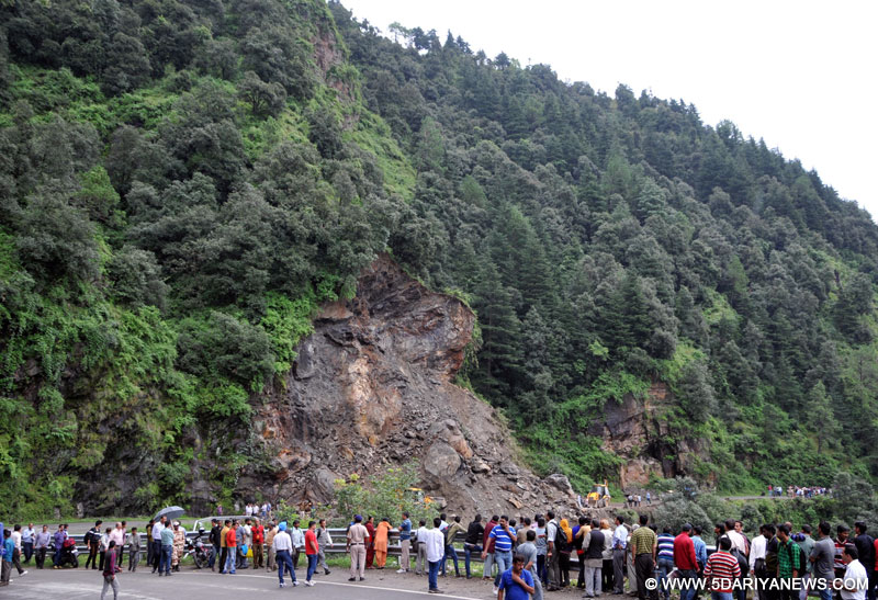 Onlookers stand on the Kalka-Shimla National highway near the site of a landslide at Shoghi near Shimla, on Aug 22, 2015. Landslide blocked the national highway causing disruption of the vehicular movement. 