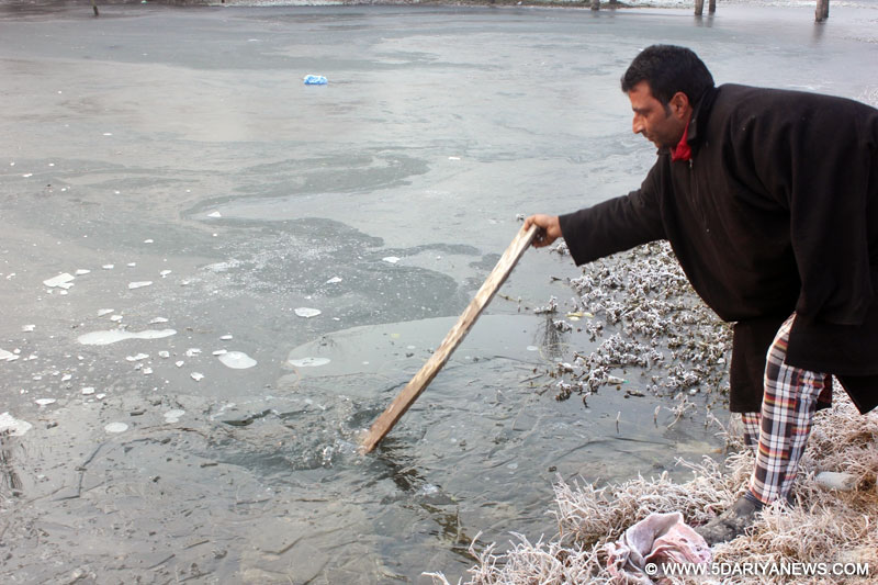 Srinagar: A man breaks the ice formed on the surface of the Dal Lake in Srinagar.