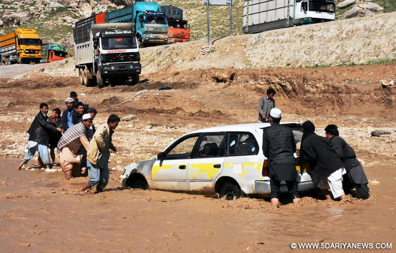 Afghan men push a car trapped in flood water after a heavy rain in Samangan province, northern Afghanistan,