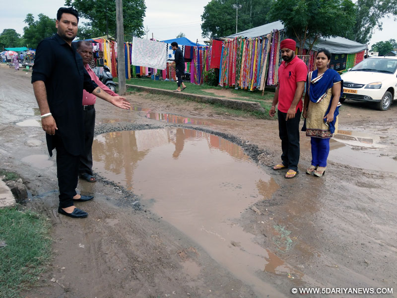बदहाल सड़क से गुजरते वाहन चालक व टूटी सड़क पर खड़ा पानी को दिखाते मंच अध्यक्ष कीरत सिंह व अन्य लोग। 