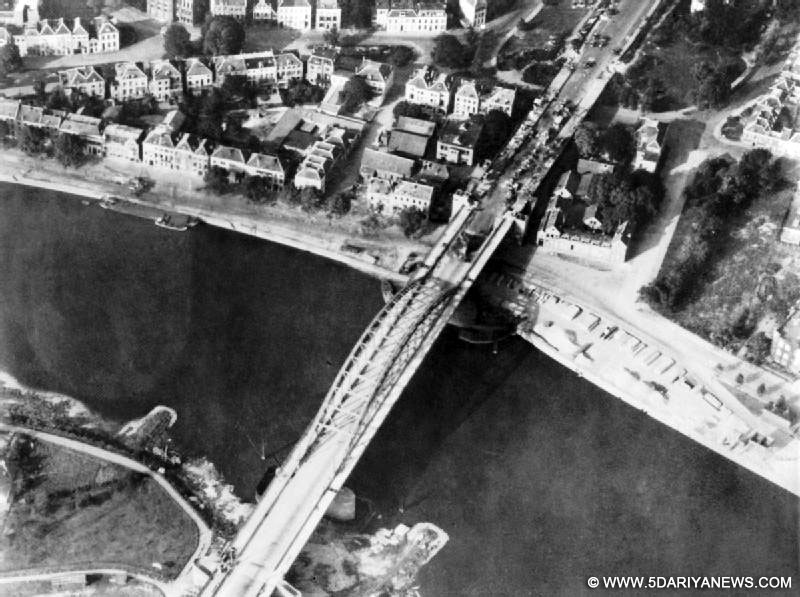 An aerial photo of the Arnhem bridge during the battle September 17-25 1944, with damaged vehicles and soldiers on one end.
